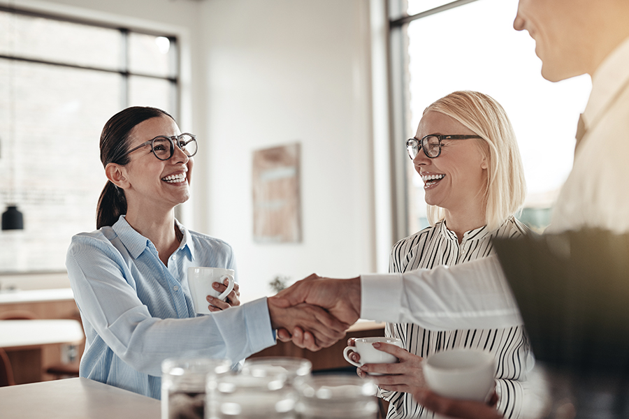 About Our Agency - Smiling Businesswomen From Goldstein Insurance Agency, LLC Shaking Hands with Colleague During Coffee Break